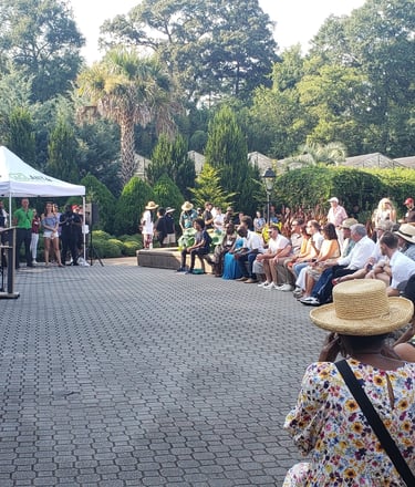 People gathered listening to speakers at the Atlanta Botanical Garden