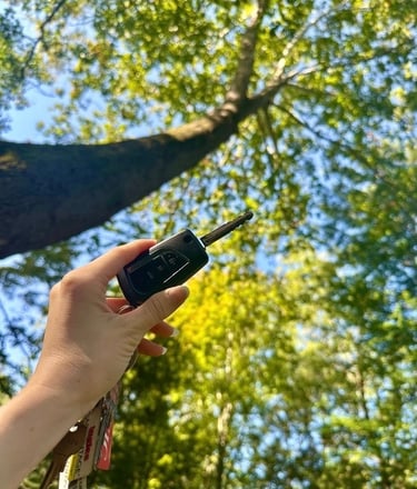 Hand holding car key fob in front of forest background— auto locksmith service Asheville, NC