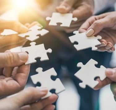 Mains tenant des pièces de puzzle, symbole d’un accompagnement complémentaire et global