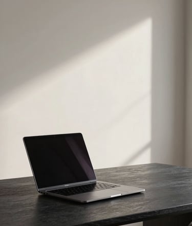 A minimalist, high-end workspace featuring a sleek modern laptop on a dark slate desk, soft natural light illuminating a clean soft off-white wall in the background, professional photography style.