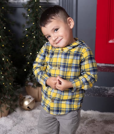 un niño pequeño sonriendo a la cámara en un set de fotos navideño