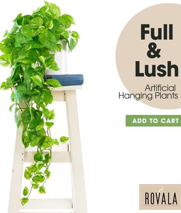 Full and lush artificial hanging pothos plant in a white pot on a wooden stool.