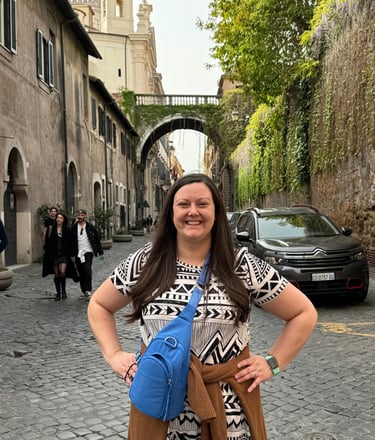 A woman standing underneath an archway on a cobblestone street in Rome, Italy