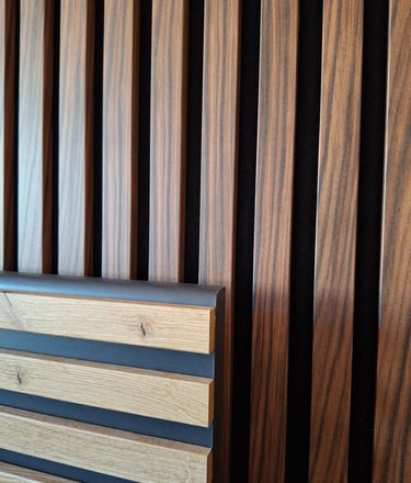 Zoom sur un raccord de panneaux en lattes de bois clair et foncé servant de tête de lit