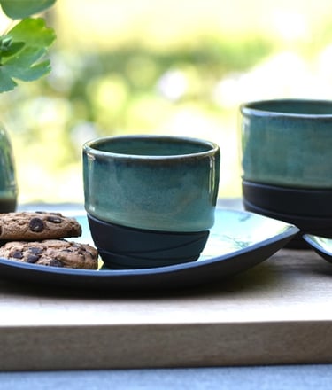 Koffie en theekopjes met schoteltjes en vaasje van handgemaakte keramiek