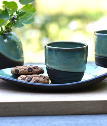 Koffie en theekopjes met schoteltjes en vaasje van handgemaakte keramiek