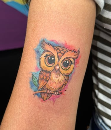 Small owl tattoo on the arm of a woman. 