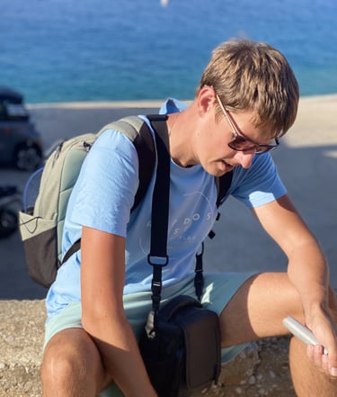a man sitting on a ledge with a camera gear in Rhodes Greece