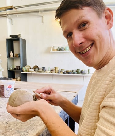 a man is smiling and holding a clay in Pottery class in Rhodes Greece