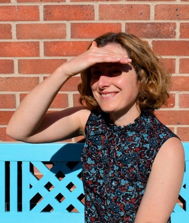 I am looking out past the camera to the garden, smiling, and shading my eyes from the sun