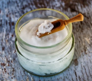 coconut oil in jar with wooden scup spoon