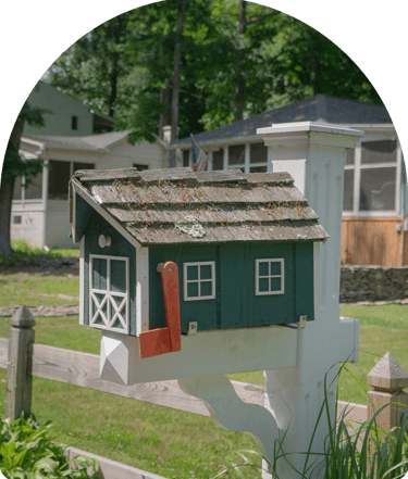 green and white handmade mailbox on a white post