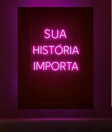 Cartaz com letras em neon na cor rosa do projeto Maria’s: Sua História Importa 