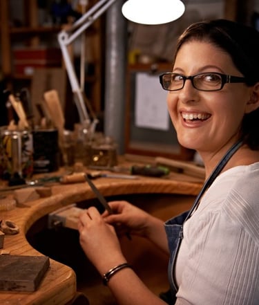 Mujer sonriendo en un taller artesanal con una lija en la mano
