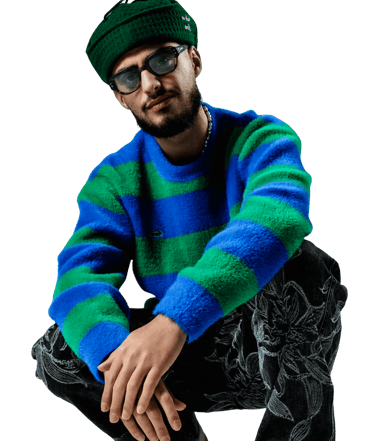 a man in a blue and green sweater and black pants