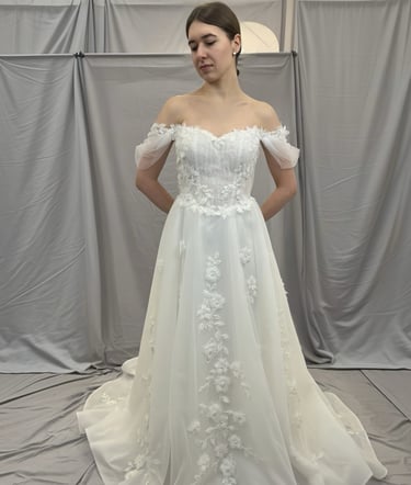 a woman in a wedding dress standing in front of a white backdrop
