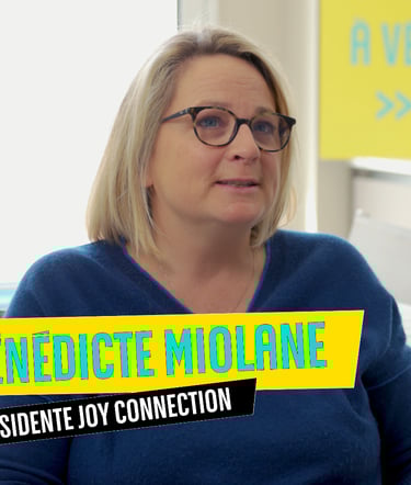 a woman in a blue sweater and glasses sitting at a desk