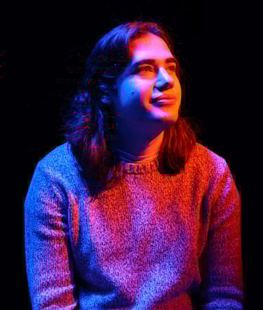 Sam Eads looking up and to the right under orange, blue and purple light