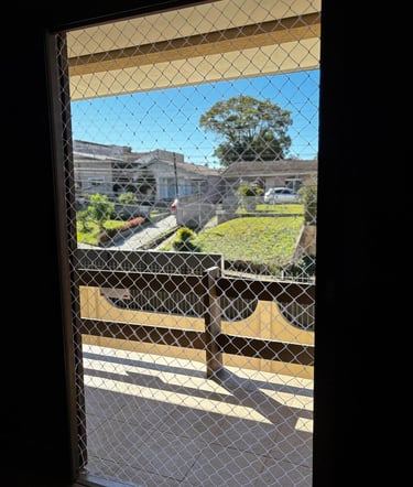 Porta da sacada vista por dentro com rede de proteção instalada.