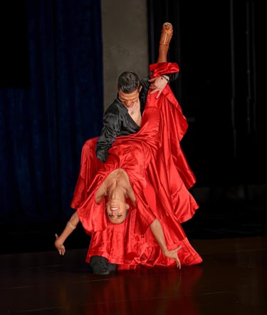 A man lifts a woman wearing a vibrant red satin skirt on the dance floor