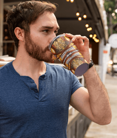 a man drinking a cup of coffee in a city