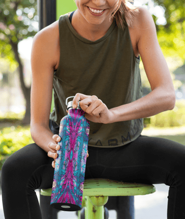 a woman sitting on a bench in a park with a water bottle that has an abstract pattern