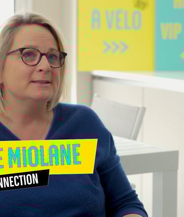 a woman in a blue sweater and glasses sitting at a desk