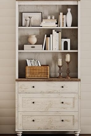 Distressed white rustic hutch cabinet and bookshelf filled with books and farmhouse decor.