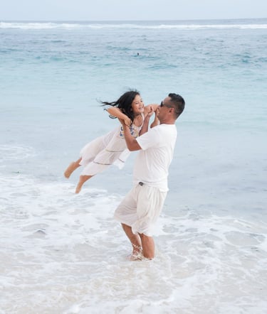 Father lifting daughter playfully in the ocean at Karma Kandara Bali  
