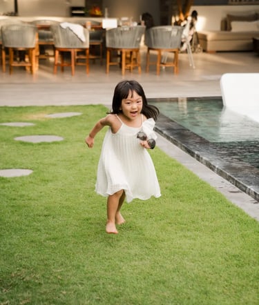 Candid lifestyle photograph of a little girl running through a tropical private villa in Seminyak Bali