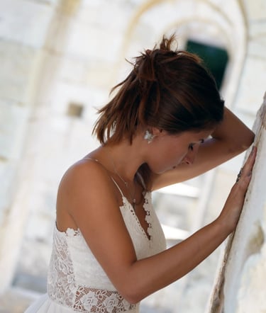 a woman in a white dress standing in front of a stone wall