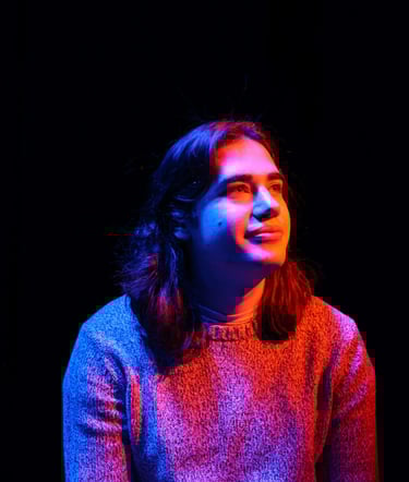 Sam Eads looking up and to the right under orange, blue and purple light