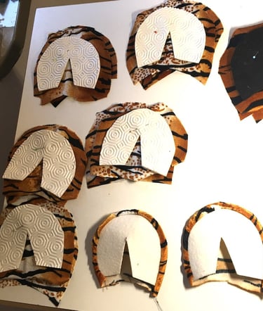 Tiger print fabric pattern pieces with white stabilizers laid out for a sewing project.