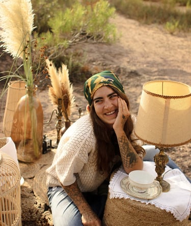 Margot Dubs Tattoo sourit, entouré d'une lampe et d'un vase, dans une lumière chaude