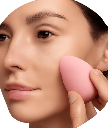A circular photograph showing a close-up of a person's face while they apply makeup to their cheek with a pink sponge.