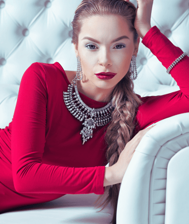 Elegant empowered woman in red dress on a white couch, symbolizing the CEO Metal Archetype in Phoenix Ignited Brand