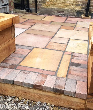 Colourful sandstone patio with raised wooden timber planter seating