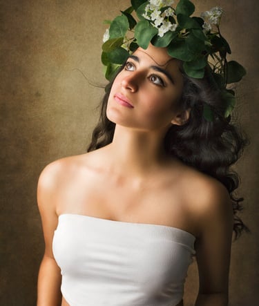 a gorgeous girl with long black curly hair looking up as the wind blows her hair away, she wears a vines crown with flowers