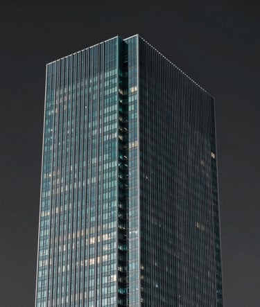 A wide, editorial shot of a minimalist, modern skyscraper corner against a deep charcoal sky. The architecture is sharp and geometric, using steel and glass. Subtle teal lighting (#0E7C7B) highlights the edges. The aesthetic is inspired by premium agency design, focused on impact and scale.