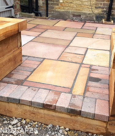 Colourful sandstone patio with raised wooden timber planter seating