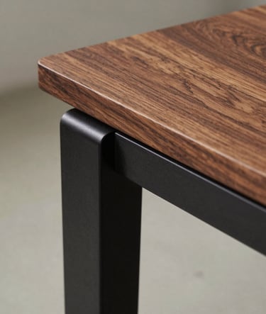 Close-up detail of a custom-designed wooden side table. The wood texture is rich and natural, contrasted with deep charcoal black metal accents. Soft, diffused daylight from the side. Editorial style, focus on tectonic details.