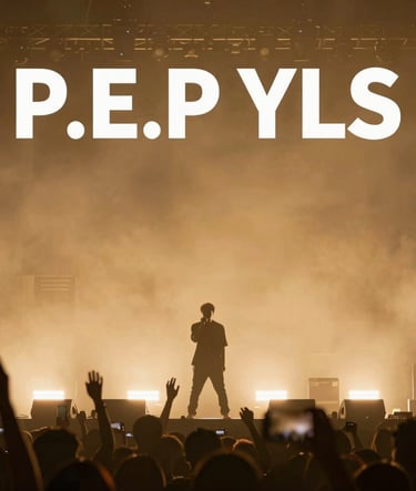 A wide-angle landscape shot of P.E.P YLS on stage during a sold-out show. The silhouette of the artist is surrounded by warm golden atmospheric lighting (#8D765D) and haze. The background shows a modern, clean stage design. Energy is palpable and powerful.
