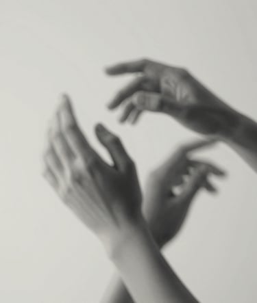 Artistic detail of hands in motion, captured with a slow shutter speed to suggest fluidity. Fine art style with a mix of #4C4A48 and #F5F2EF tones, emphasizing the elegance of human form.