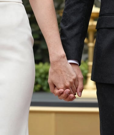 An artistic close-up photography of a couple's hands joined together, featuring elegant attire in charcoal black and soft off-white. Photographed in a modern garden in Istanbul with luxury gold accents in the soft-focus background.