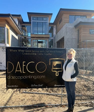 Daeco Painting representative standing at a luxury new construction site next to a company banner re