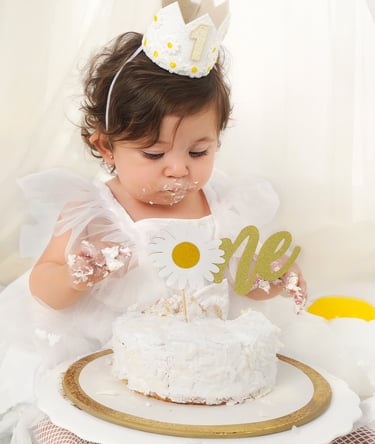 Adorable baby covered in frosting, enjoying a colorful cake smash birthday photoshoot.