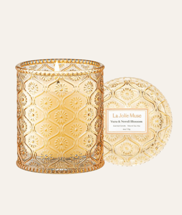 picture of La Muse Jolie peach colored glass candle jar with lid on the side
