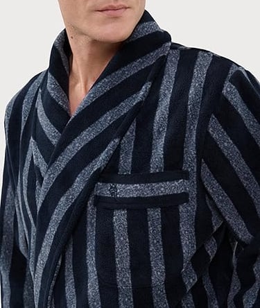 Un hombre con una bata de felpa de rayas verticales azul marino y gris, con cuello chal.