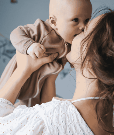 una madre levanta a su bebé en sus brazos feliz de hacerse la prueba NIPT en Colombia