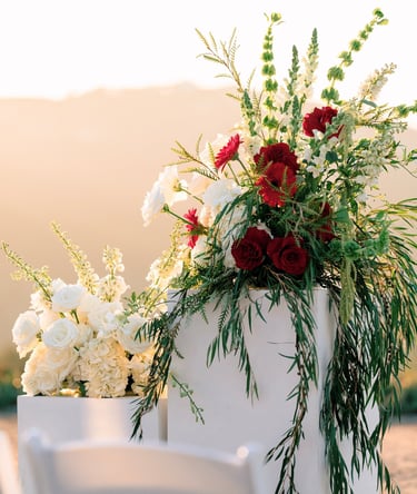 red and white wedding arrangements on white pedestals